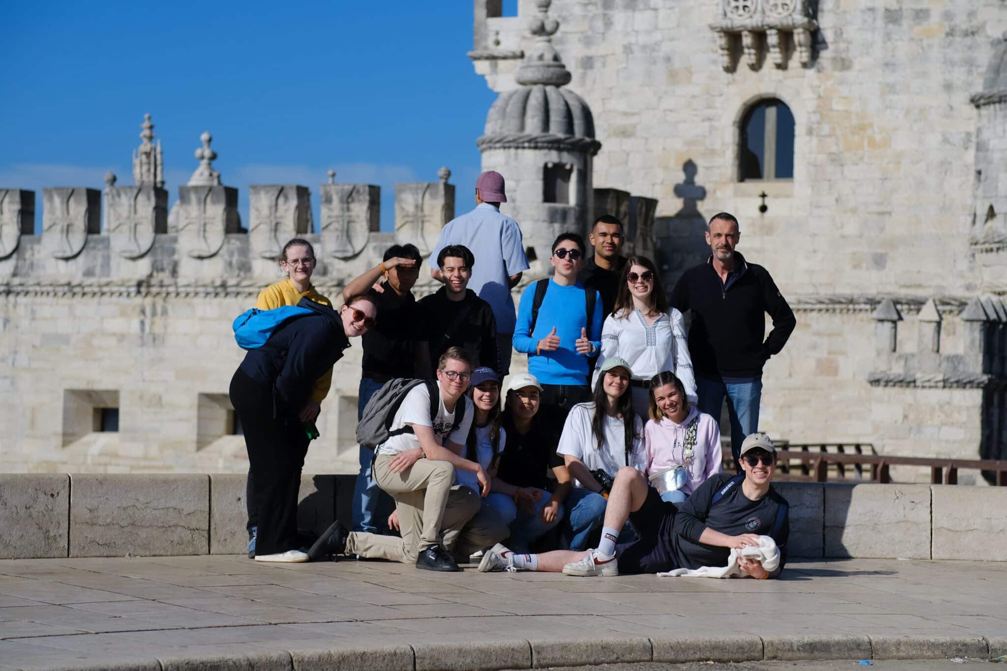 des étudiants et leurs professeurs posent devant un monument de Lisbonne